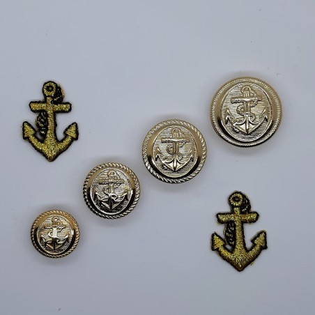 Botón decorativo con dibujo de ancla dorado metálico con pie. 