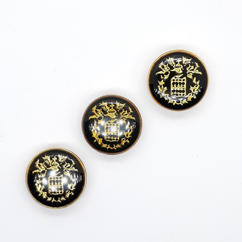 Botón metálico de 2 cms con escudo decorativo.