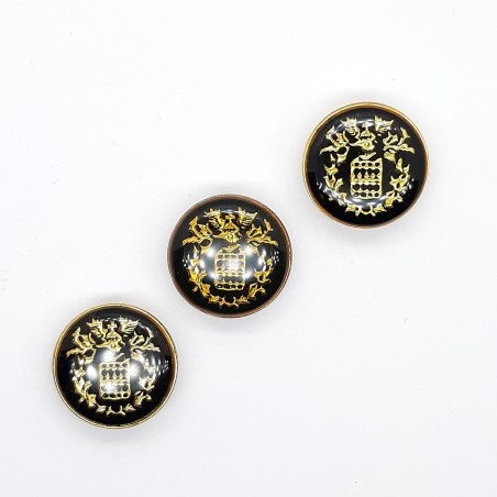 Botón metálico de 2 cms con escudo decorativo.